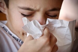 Boy blowing his nose in a tissue