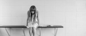 Woman sitting on a bench looking down sad and depressed.