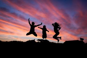 Happy people jumping in the air with the sunset behind them