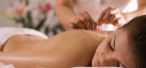 Relaxed woman receiving acupuncture treatment on her back in a serene spa setting, promoting holistic health and relaxation.