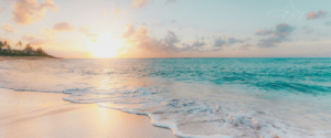 Waves on the beach with sunset in the background.