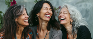 Three vibrant women sharing a joyful moment, celebrating friendship and life during midlife. This image highlights the strength, connection, and beauty women embrace during the perimenopause and menopause phases.