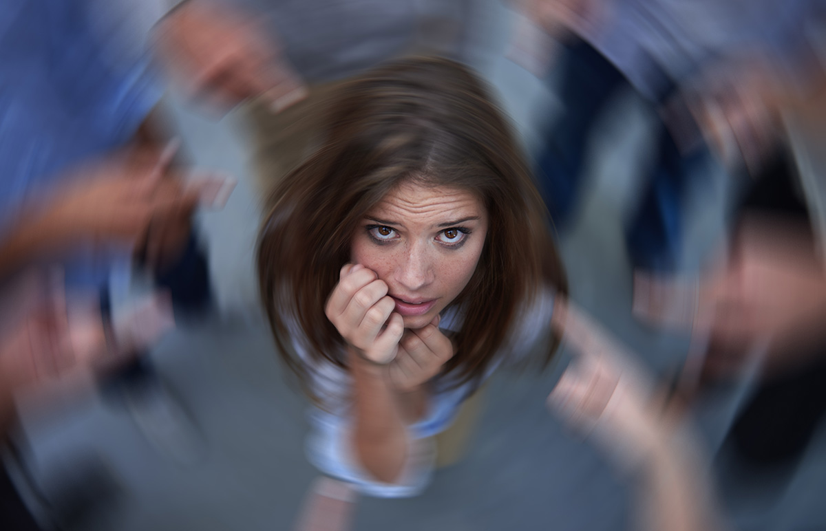 Conceptual shot of an anxious young woman in the middle of a circle of accusing coworkers.