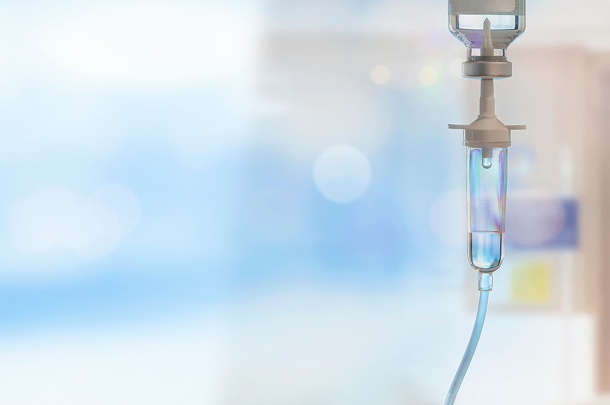 Close-up of a hospital IV drip with clear liquid, set against a blurred background of a medical facility, symbolizing hydration therapy and healthcare services.