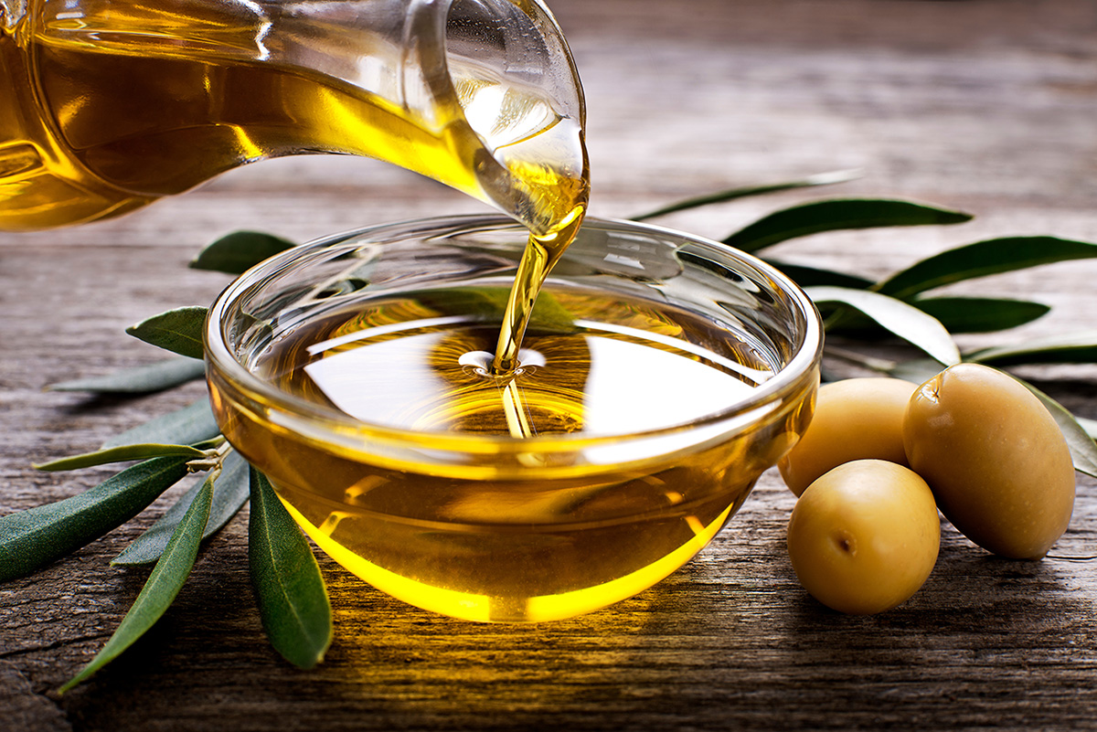 Bottle pouring virgin olive oil in a bowl close up