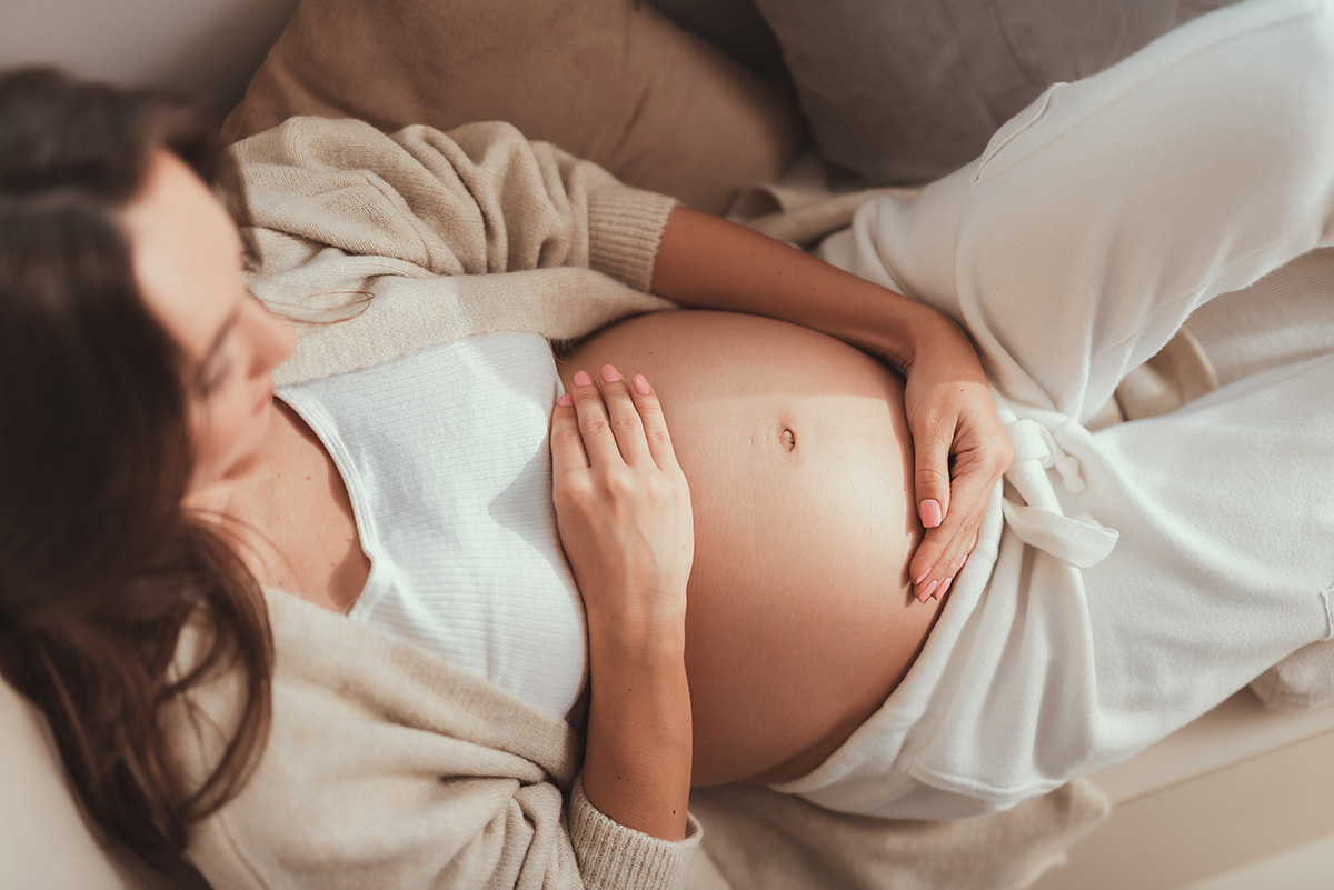 High angle above top view beautiful attractive pretty expectant mother on third trimester lying on cozy couch inside bright flat