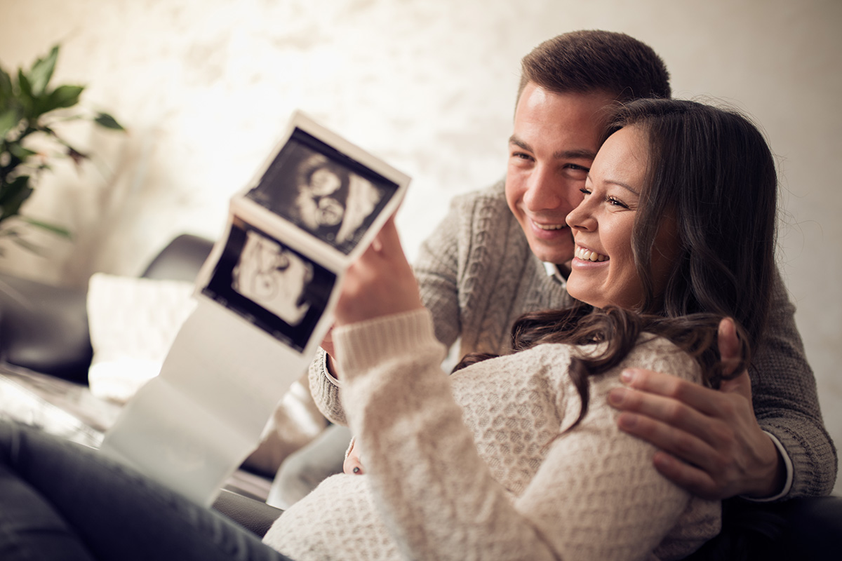 Young pregnant couple looking at ultrasound image.