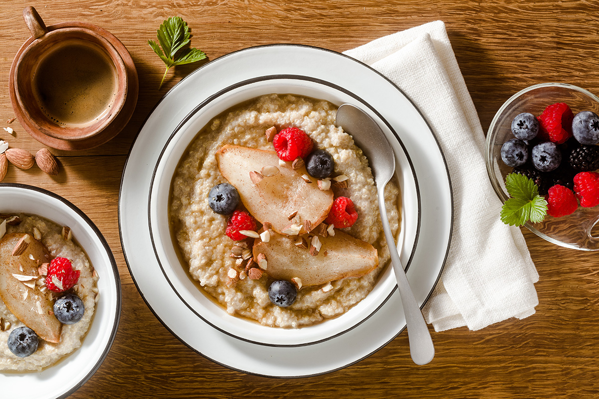 quinoa porridge with caramelized pear and berries on a wooden table. morning breakfast with coffee