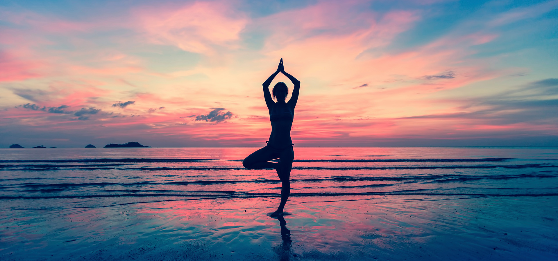 Silhouette of woman standing at yoga pose on the beach during an amazing sunset.