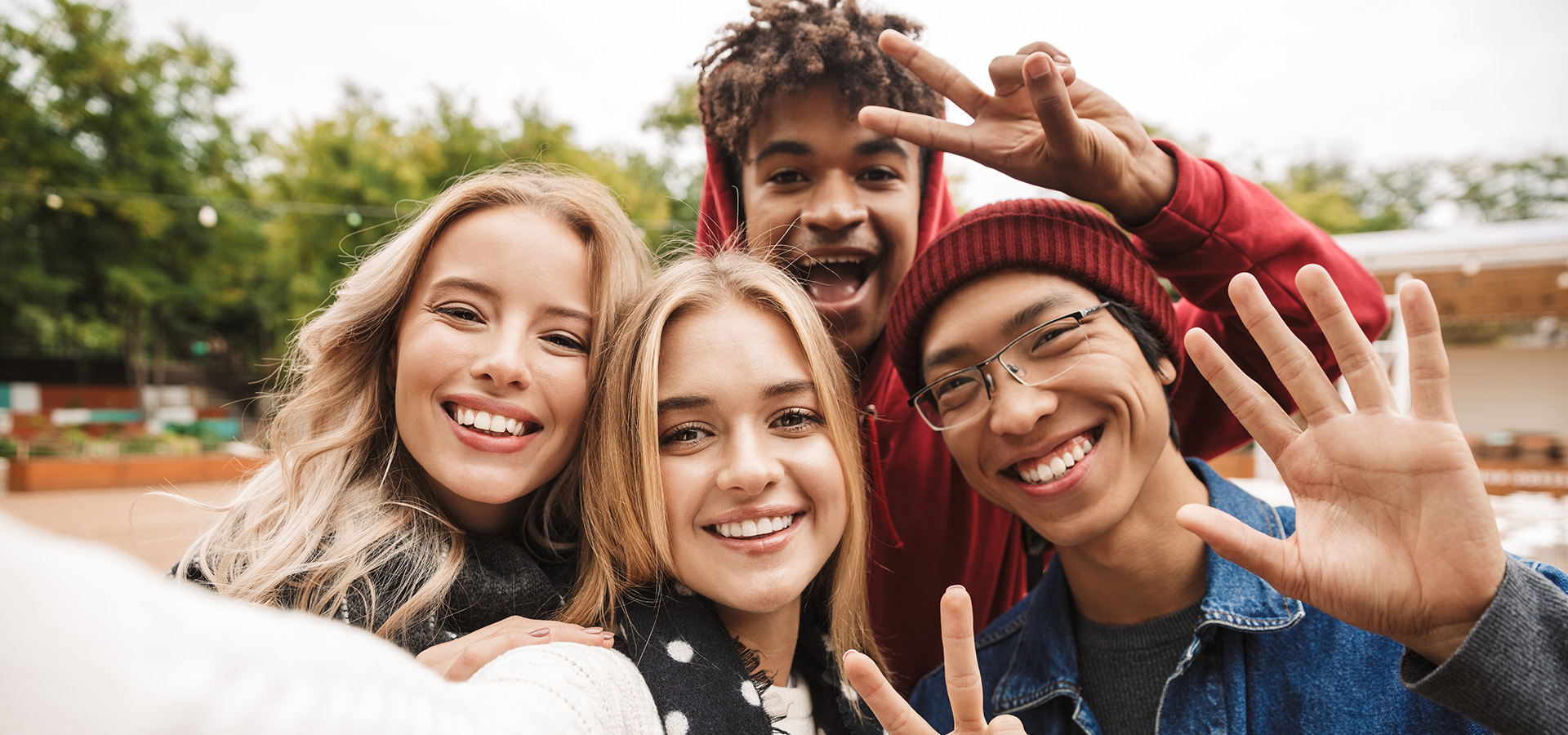 Group if cheerful teenagers spending fun time together outdoors, taking a selfie.