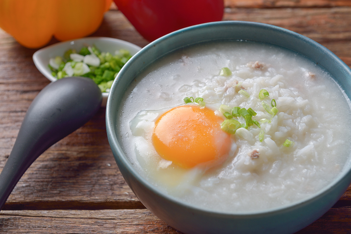 Thai chinese asian rice porridge with pork and egg in bowl