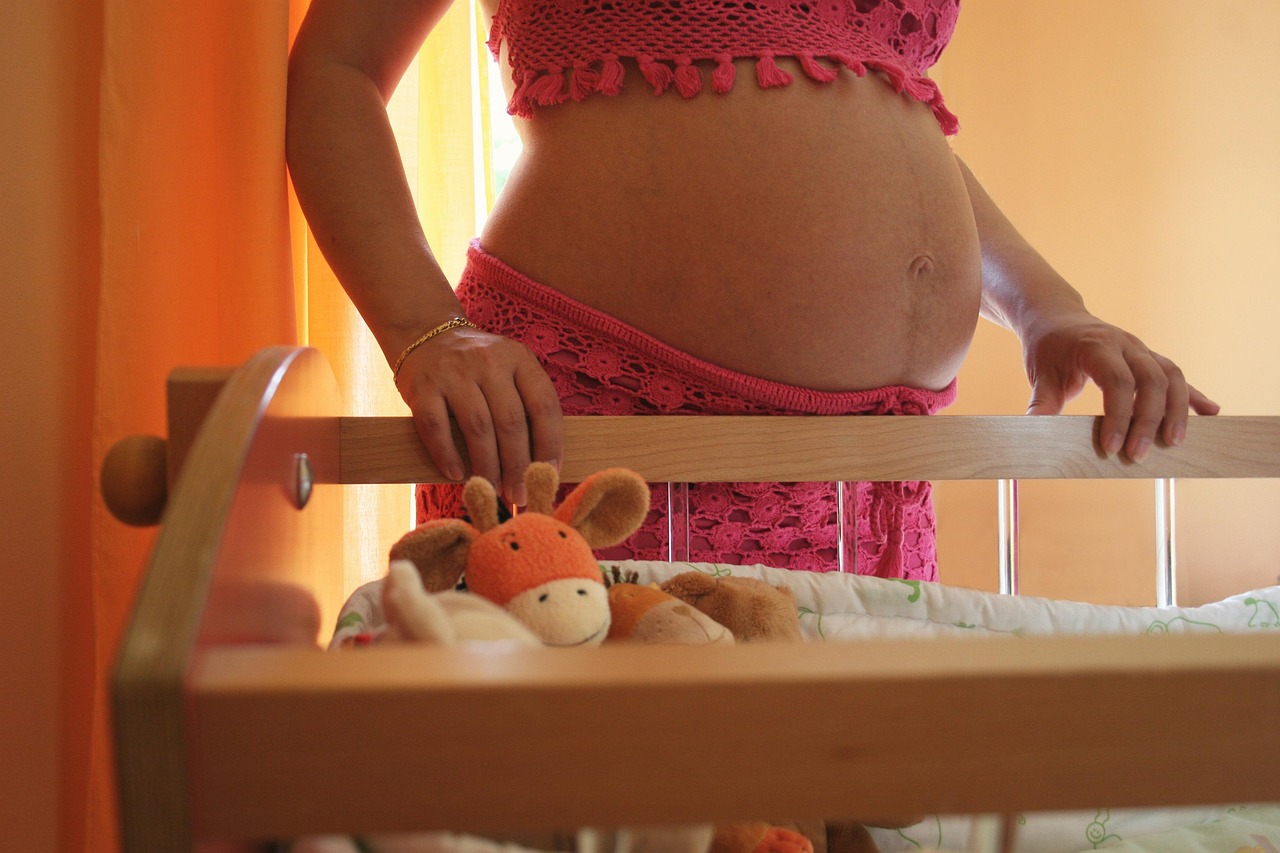 Pregnant woman standing next to a crib