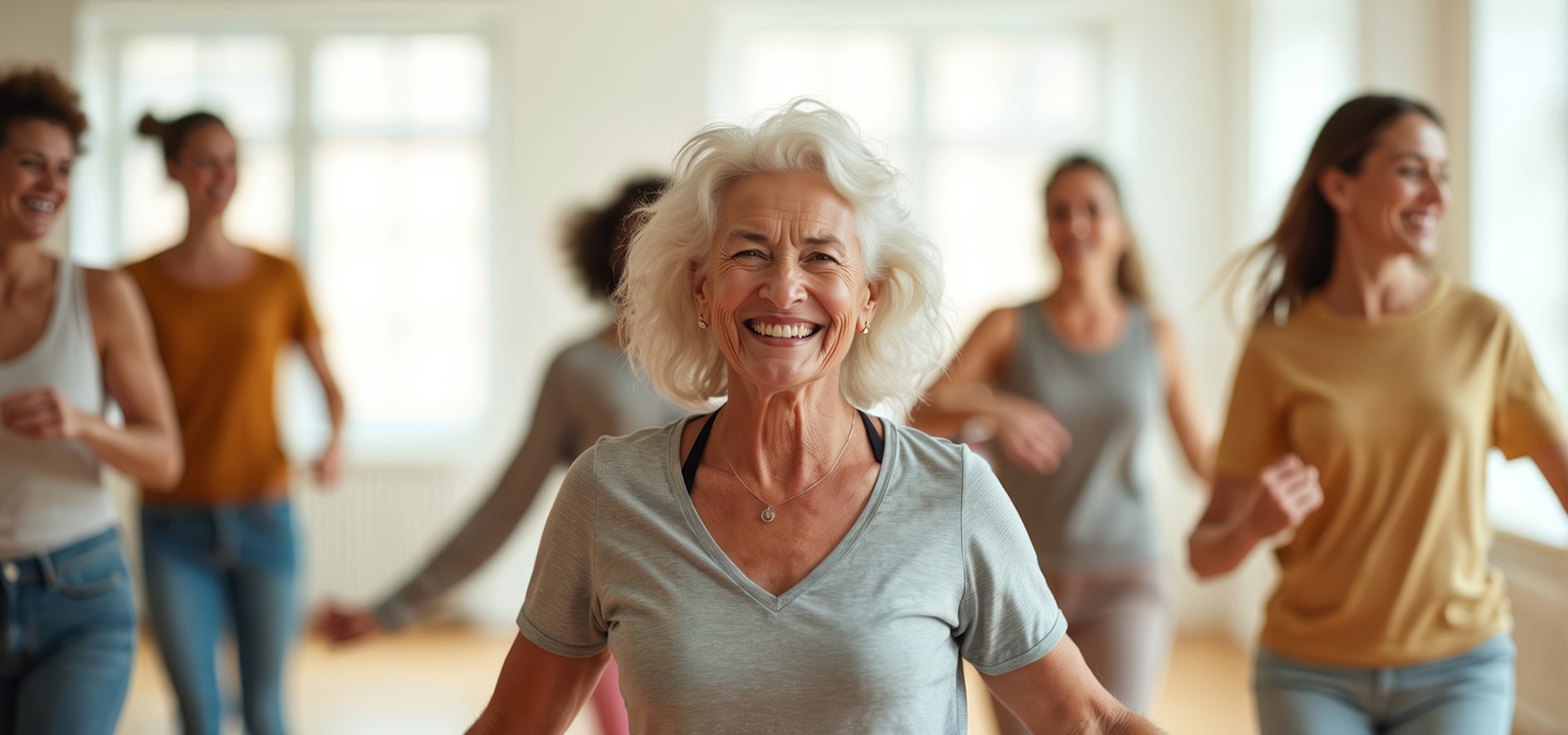 Senior woman smiles, dances in class with group of diverse people.