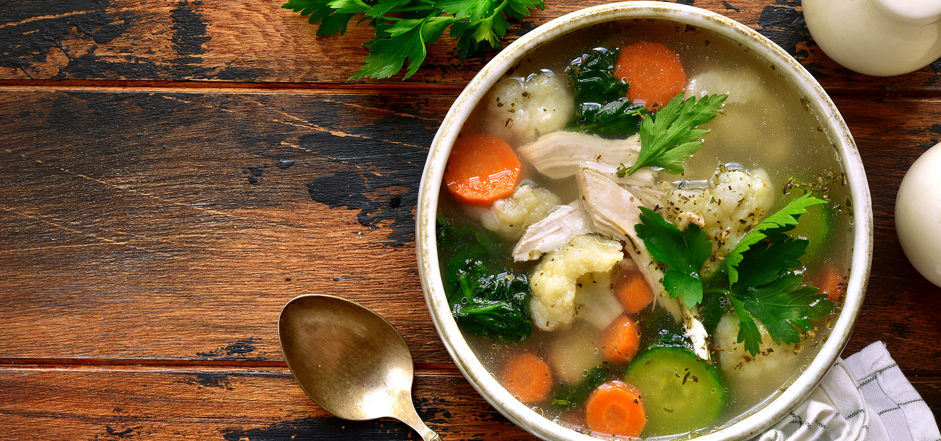 Vegetable soup with chicken fillet in a bowl over dark rustic wooden background.