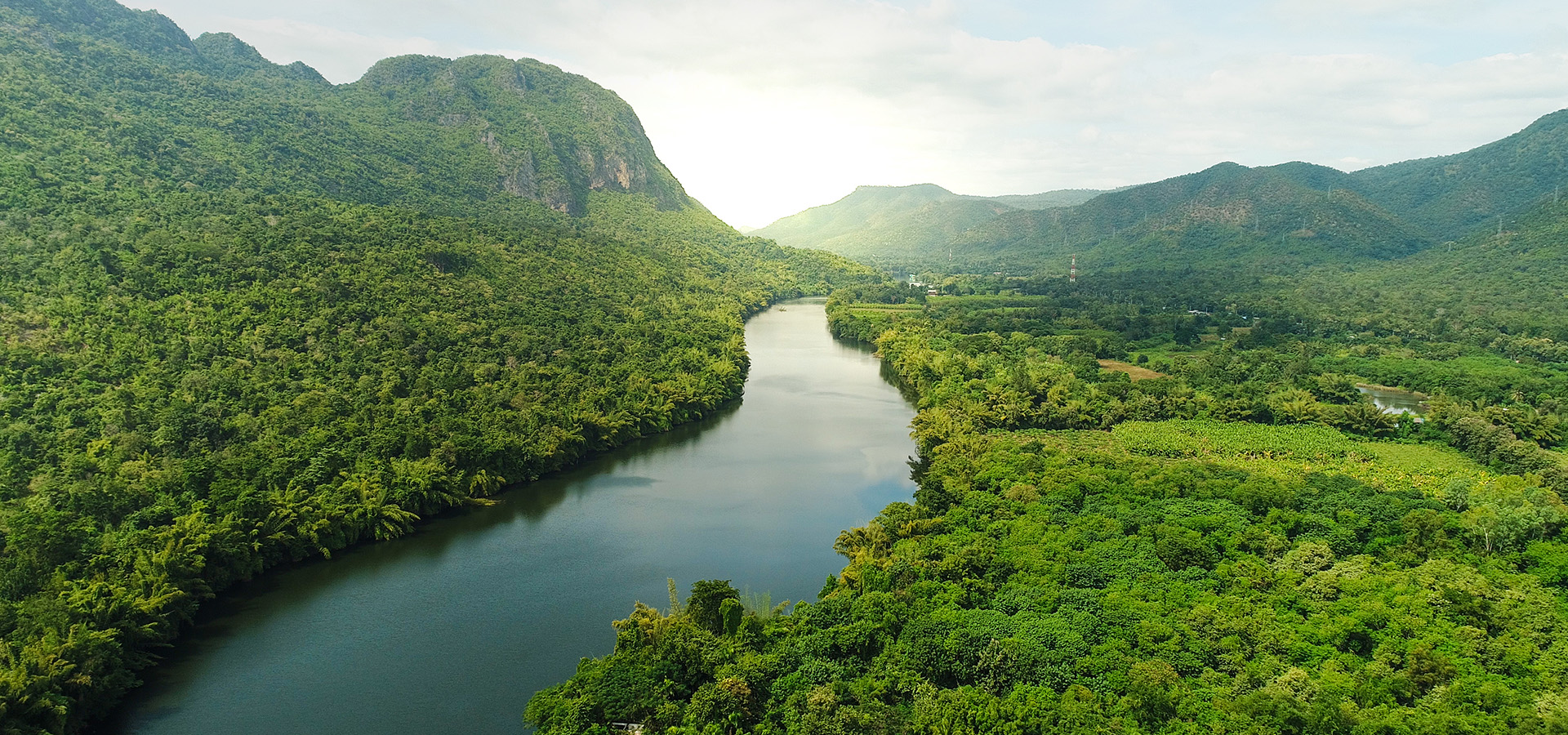 Beautiful natural scenery of river in southeast Asia tropical green forest with mountains in background